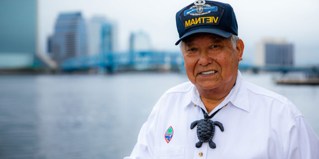 Older male patient by the bay smiling with their new dental implants