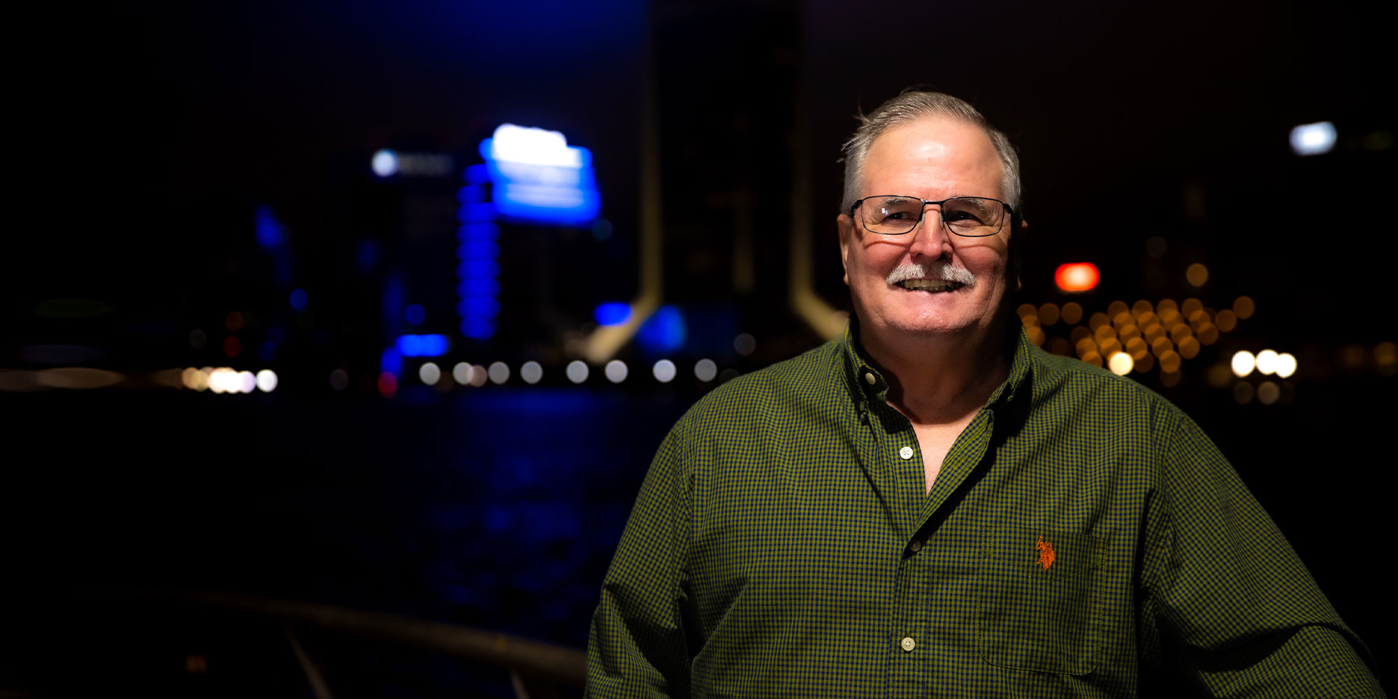 Older male patient smiling with their new implants under lighting