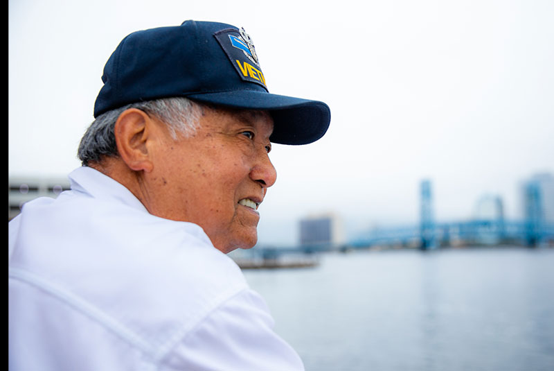 Older male patient looking out into the bay smiling with their new implants